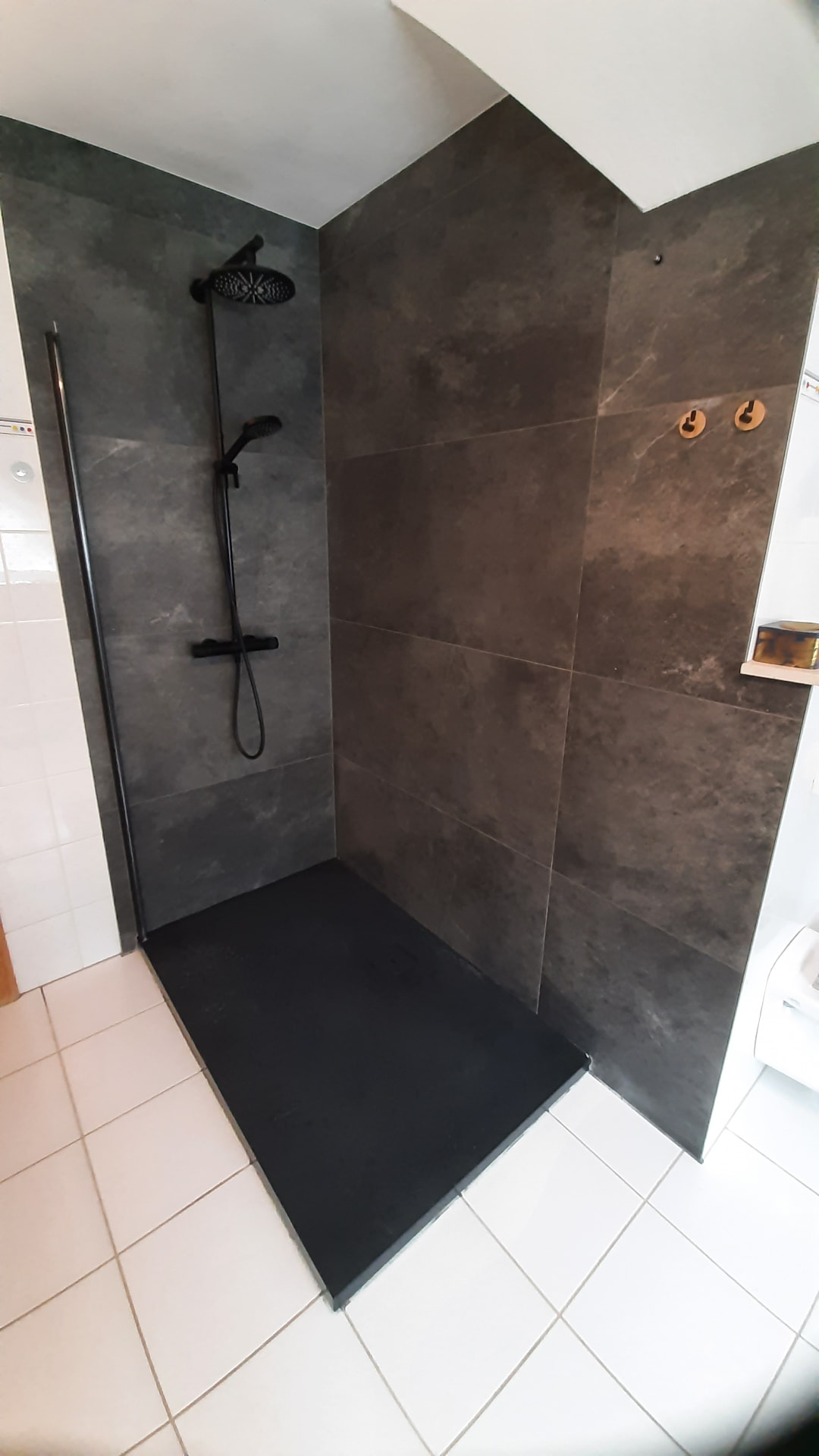 Dunkle bodengleiche Dusche mit schwarzem Duschsystem und großformatigen Wandfliesen
